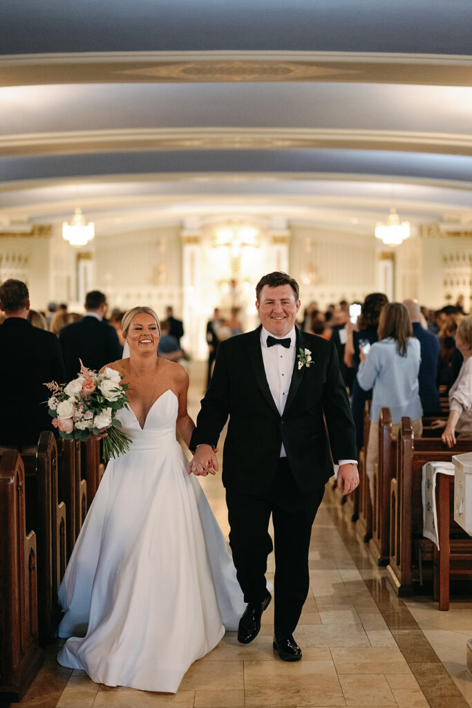 Bride and groom walking back down the aisle as husband and wife after their Catholic wedding ceremony