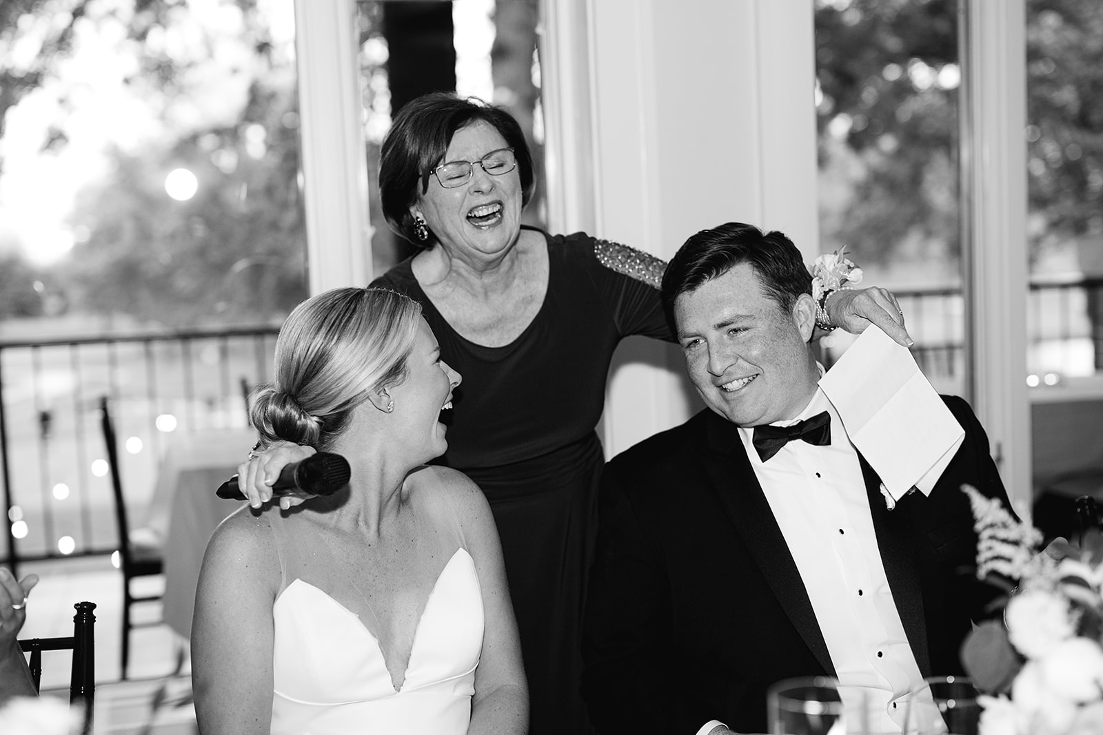 Black and white photo of a bride and groom laughing during speeches