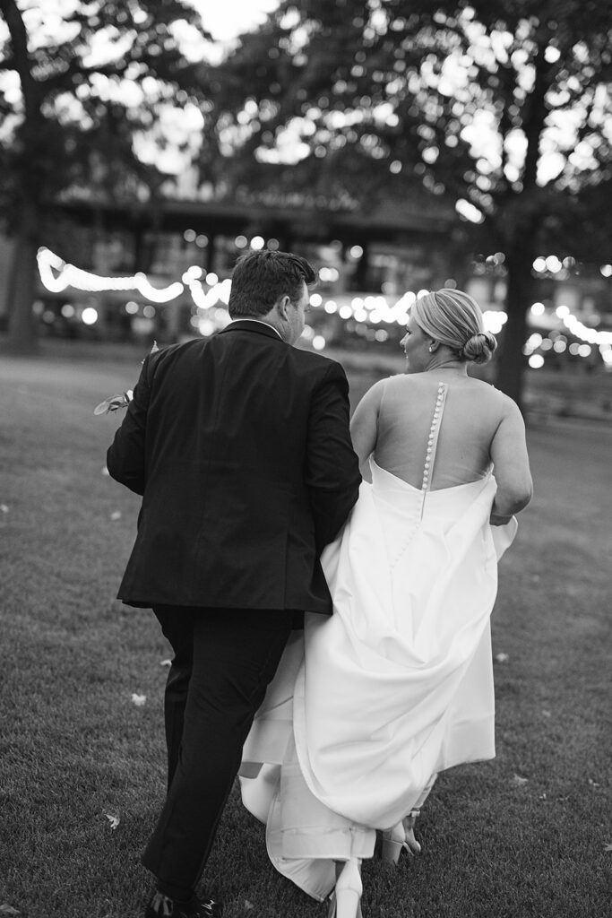 Black and white photo of a bride and groom walking back to their River Forest Country Club wedding in Chicago