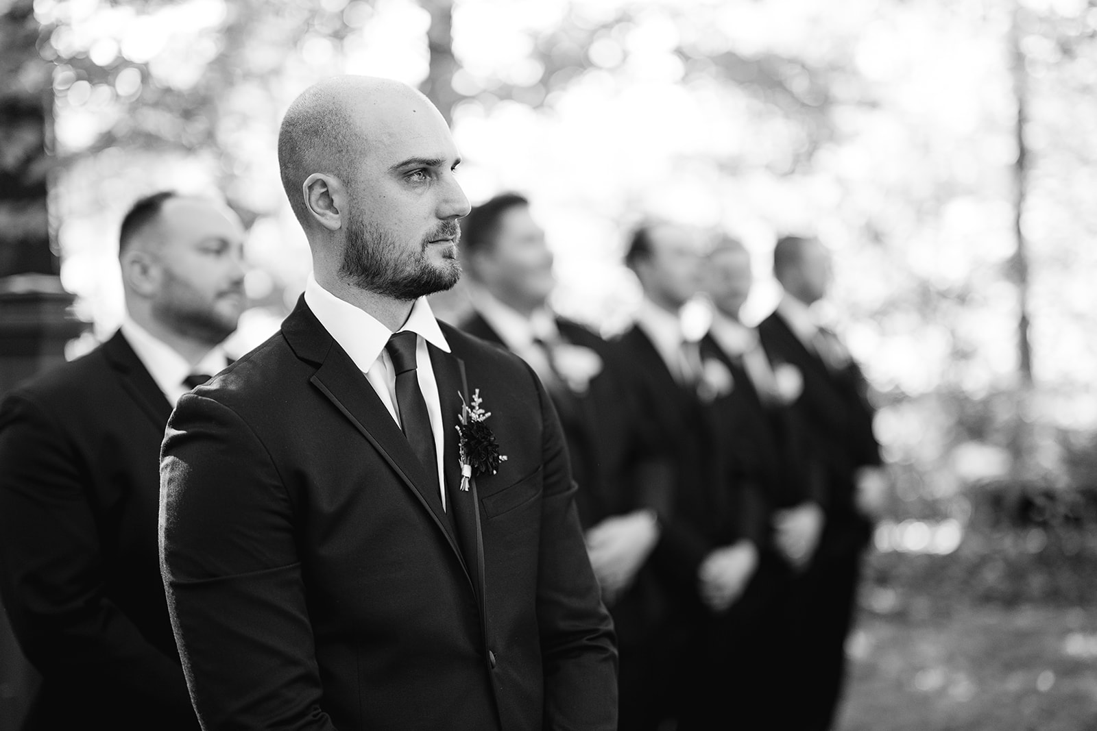 Black and white photo of a groom seeing his bride walking down the aisle