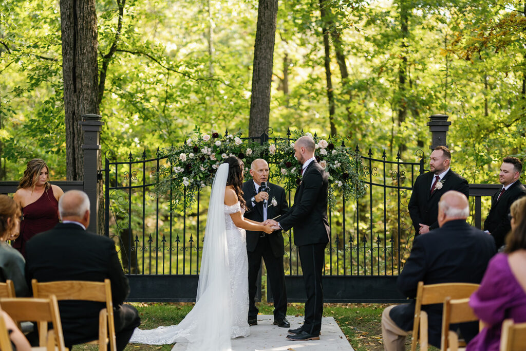 Bride and groom holding hands during their outdoor fall Ritz Charles wedding ceremony in Indianapolis, Indiana