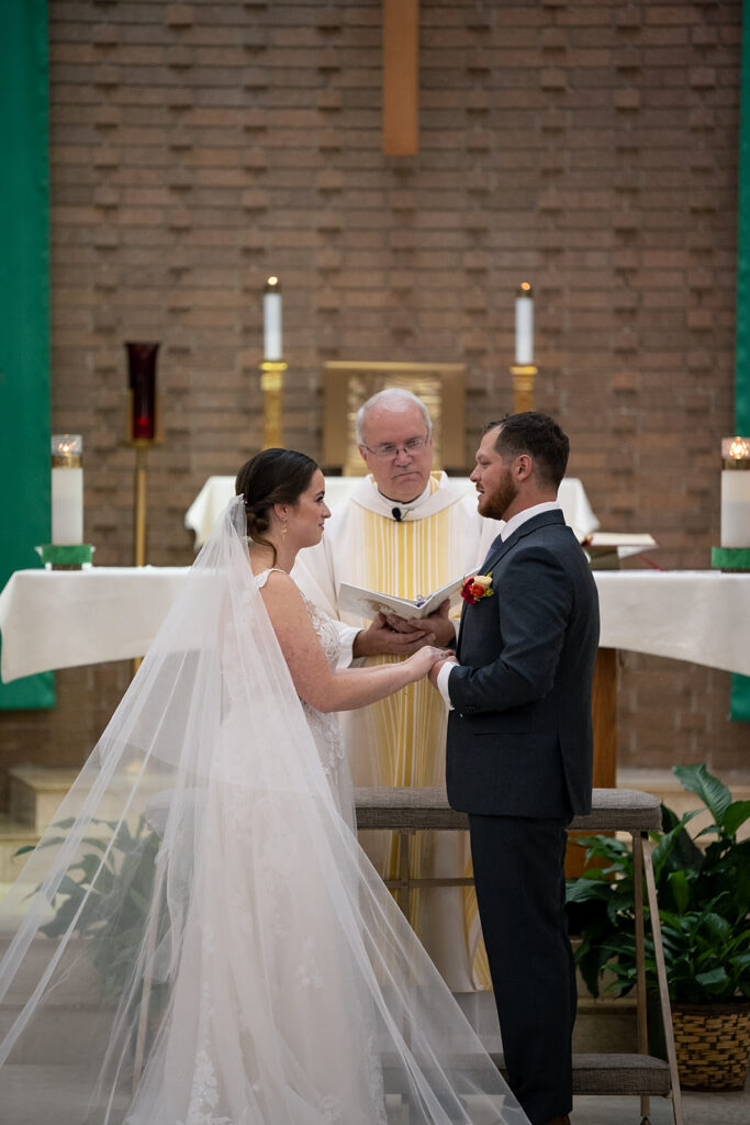 Bride and groom holding hands during their Catholic wedding ceremony