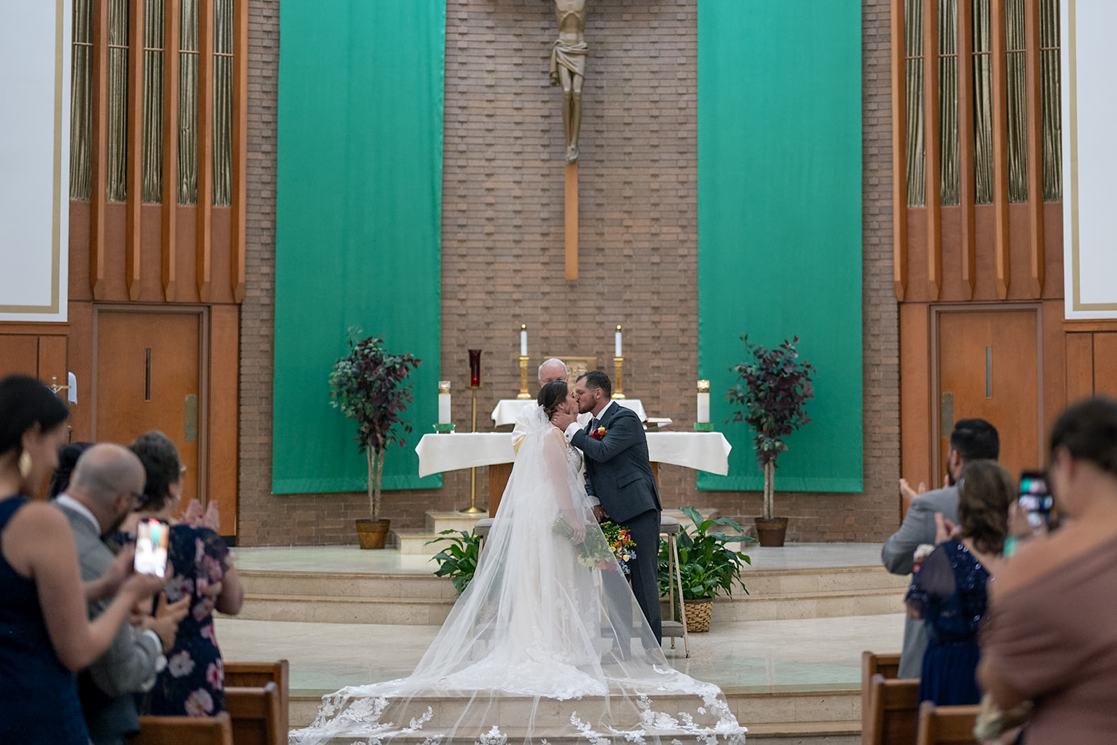 Bride and groom kissing during their Catholic wedding ceremony