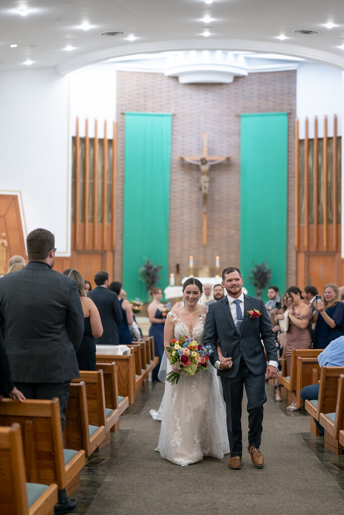 Bride and groom walking down the aisle as husband and wife during their Catholic wedding ceremony