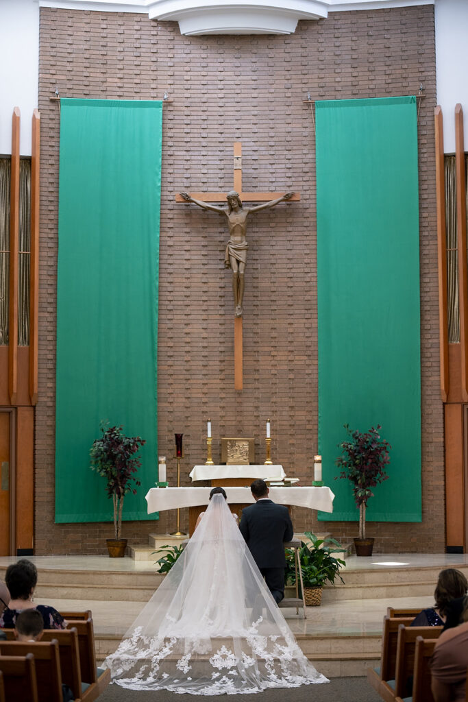 Bride and groom kneeling during their Catholic wedding ceremony in Chicago