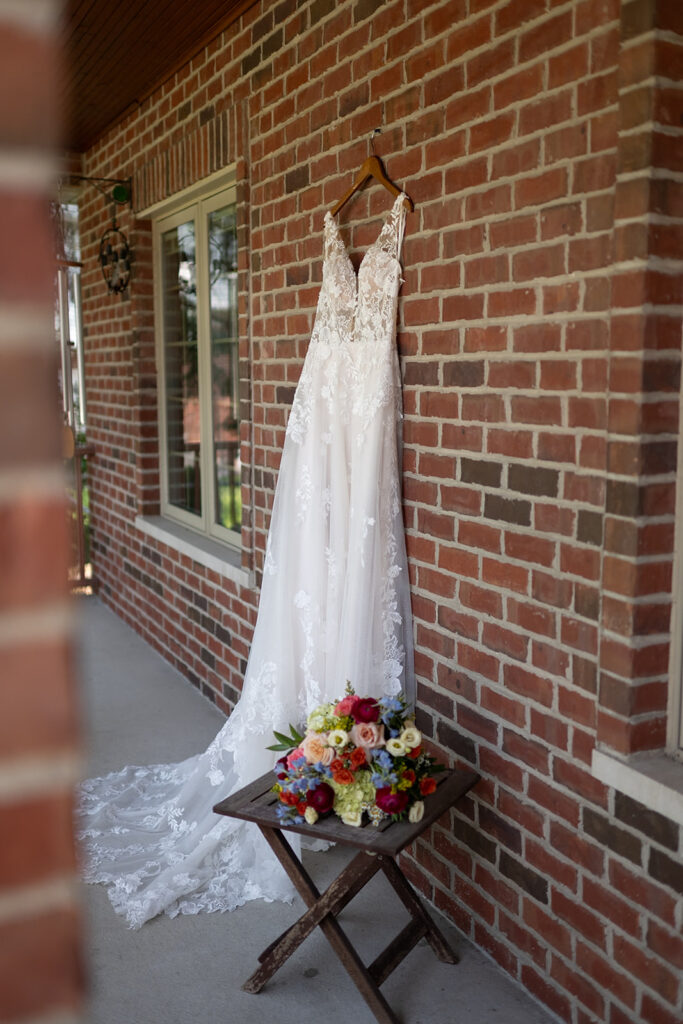 Wedding dress hanging with bouquet next to it