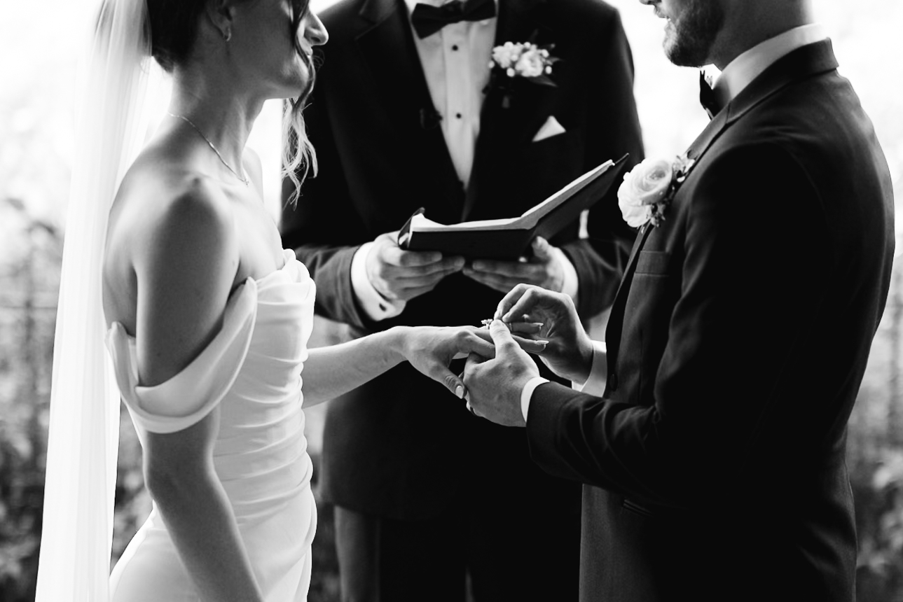 Black and white photo of a bride and groom exchanging rings