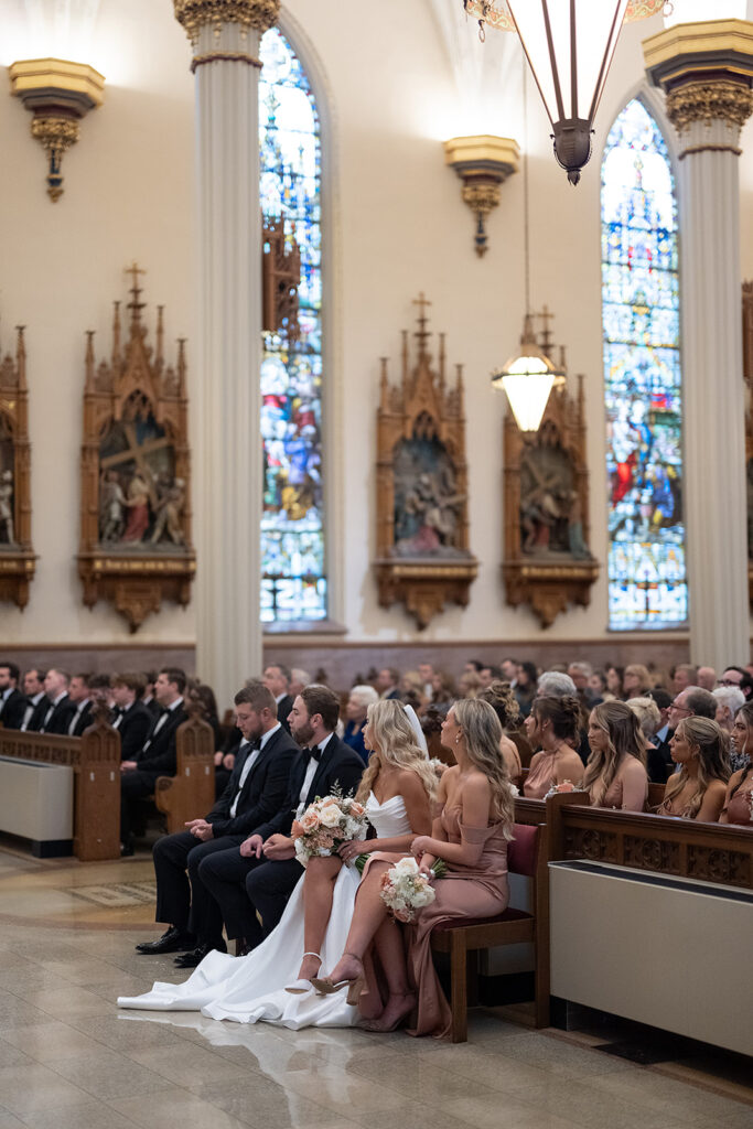 Bride and groom sitting in pews during their Immaculate Conception Fort Wayne wedding ceremony