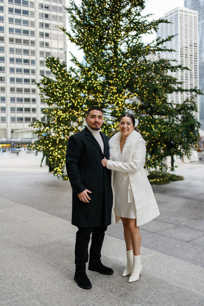 Couple posing in front of the tree during their winter downtown Chicago engagement photos