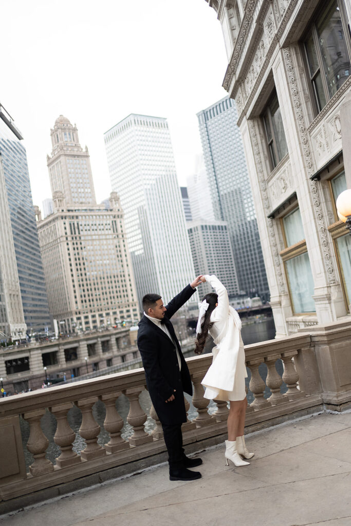 Man twirling his fiancé on the DuSable Bridge for their downtown Chicago engagement photos in the winter