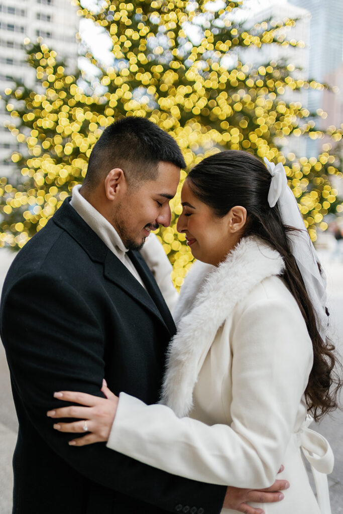 Couple posing in front of the tree during their winter downtown Chicago engagement photos