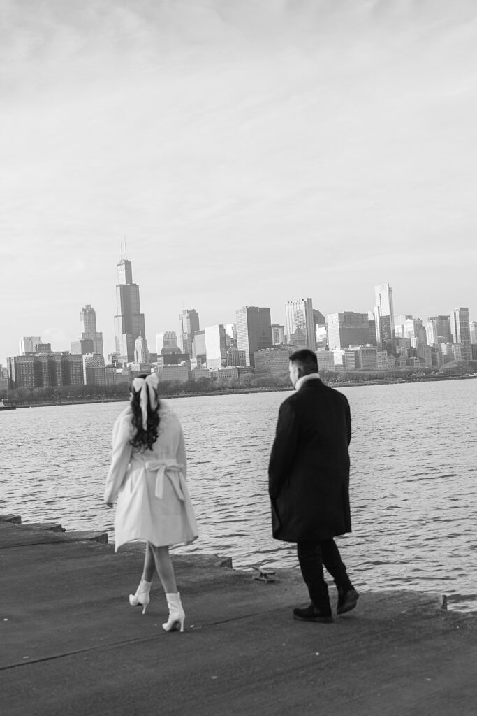 Black and white photo of a couple walking lakefront for their Chicago engagement photos