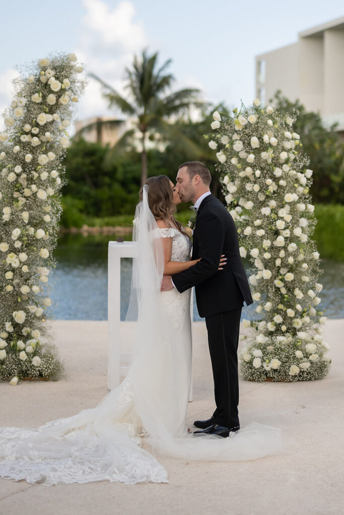 Bride and groom kissing during their outdoor Grand Palladium Costa Mujeres wedding ceremony at Deck in The Village