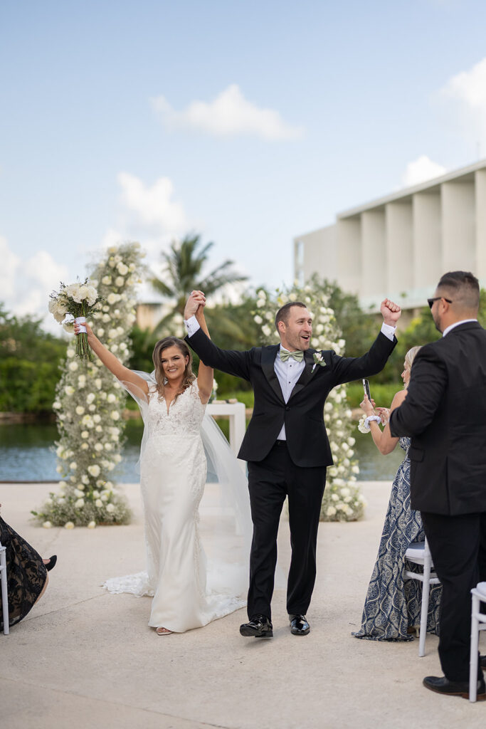 Bride and groom walking back down the aisle as husband and wife after their outdoor Grand Palladium Costa Mujeres wedding ceremony at Deck in The Village