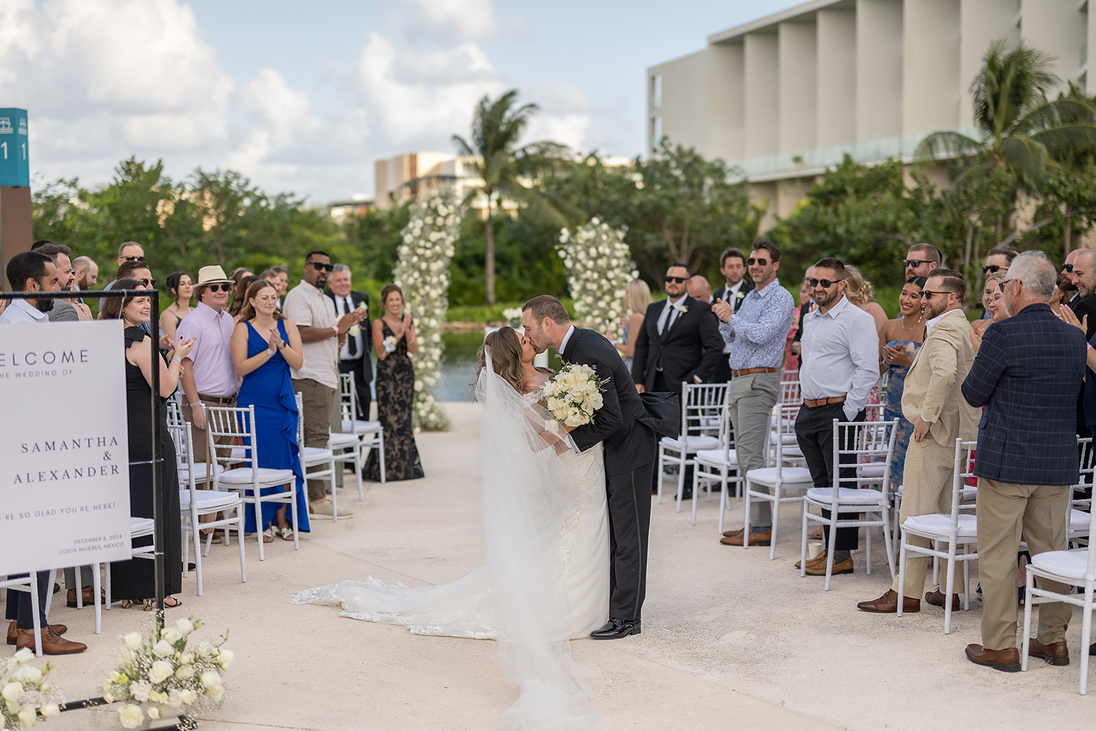 Bride and grooms end of aisle kiss during their outdoor Grand Palladium Costa Mujeres wedding ceremony at Deck in The Village