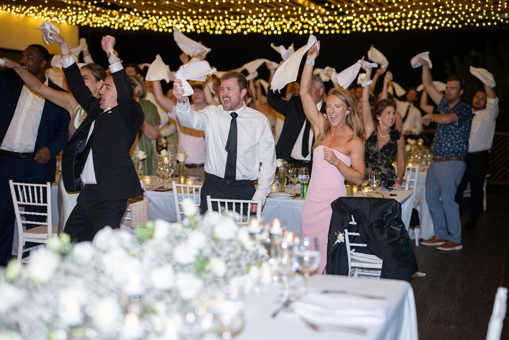 Wedding guests waving napkins as couple enters the reception