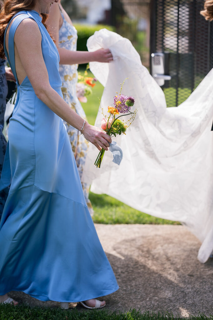 Candid wedding photo of a the bridesmaids holding the brides train as she walks