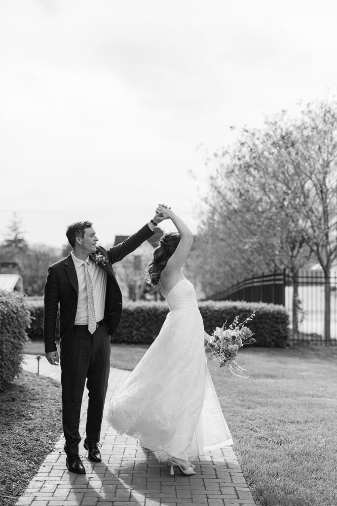 Black and white photo of a groom twirling his bride