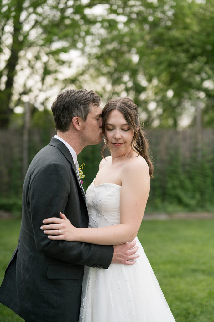 Groom kissing his bride during their outdoor wedding portraits