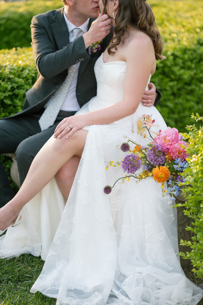 Bride and groom kissing while sitting on a bench