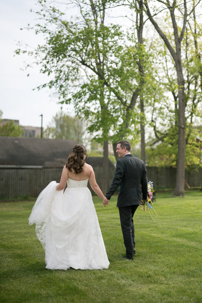 Bride and groom walking together on an open grassy area