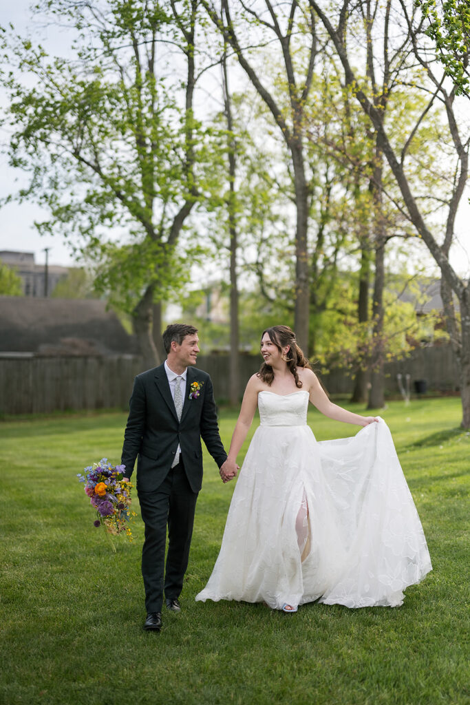 Bride and groom walking together on an open grassy area