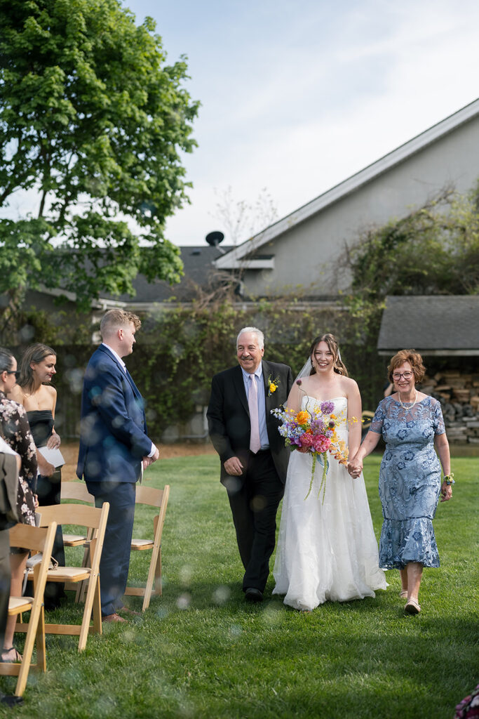 Bride walking down the aisle with her mother and father for her Bunn House wedding ceremony in Asheville, NC