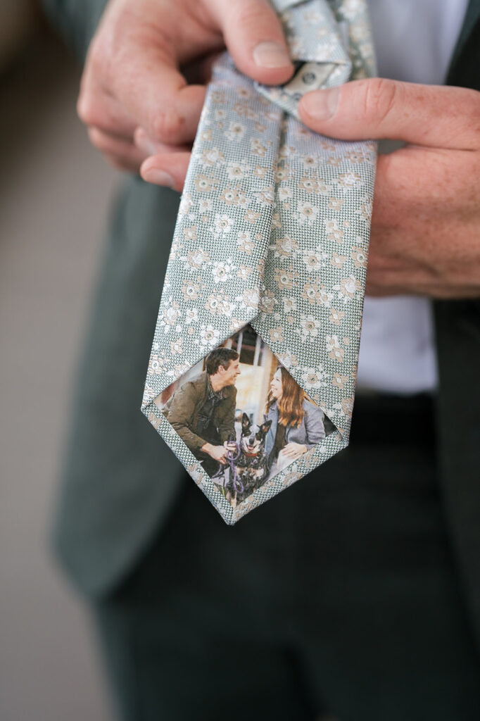 Groom showing off his custom floral tie with him, the bride, and their dog