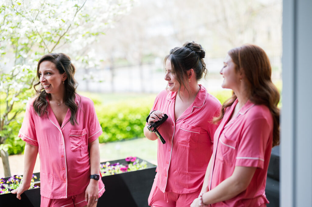 3 bridesmaids smiling as the bride gets ready