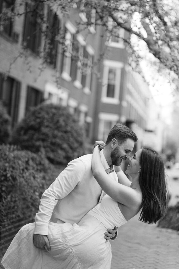Black and white engagement photo of a couple smiling at each other