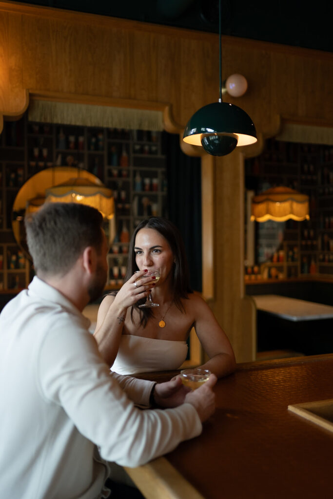 Couple having drinks for their Washington DC engagement photos at a cocktail bar