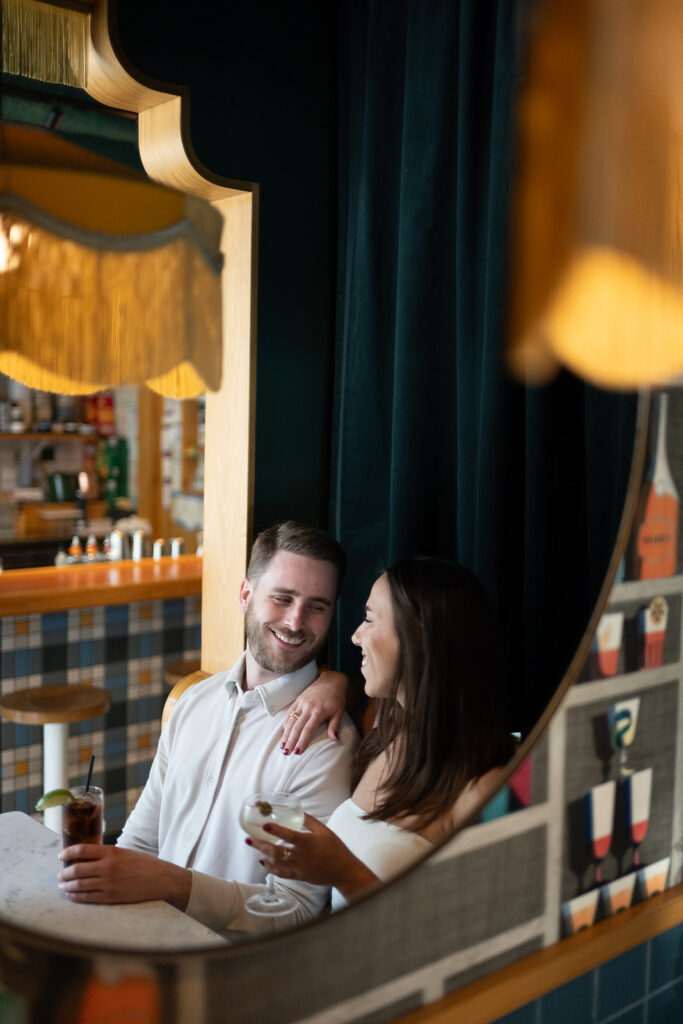 Couple having drinks at a cocktail bar for their engagement photos in Washington DC