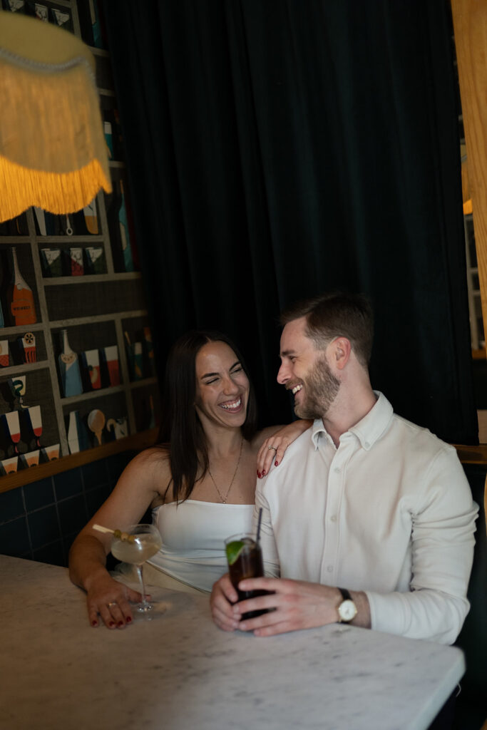 Couple cuddled up together in a booth at Jane Jane for their engagement photos in Washington DC