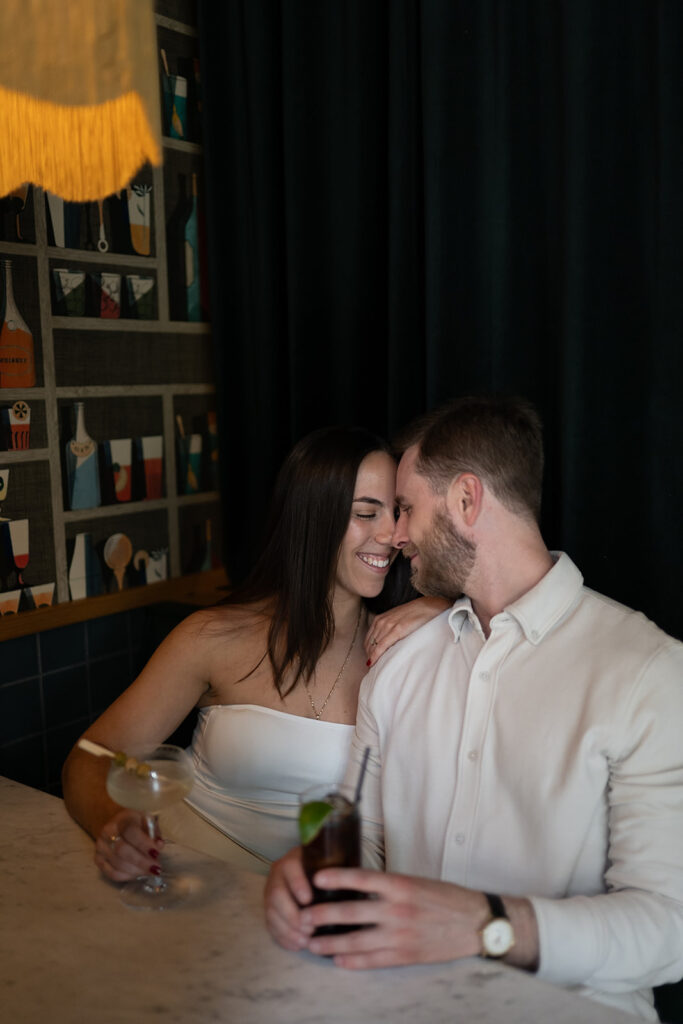 Couple cuddled up together in a booth at Jane Jane for their engagement photos in Washington DC