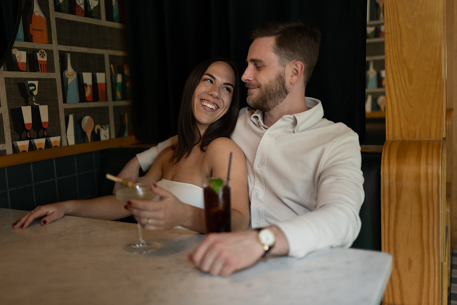 Couple cuddled up together in a booth at Jane Jane for their engagement photos in Washington DC