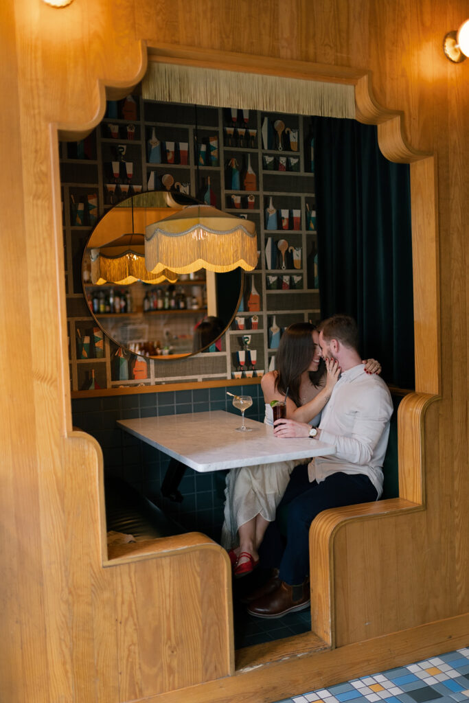 Couple cuddled up together in a booth at Jane Jane for their engagement photos in Washington DC