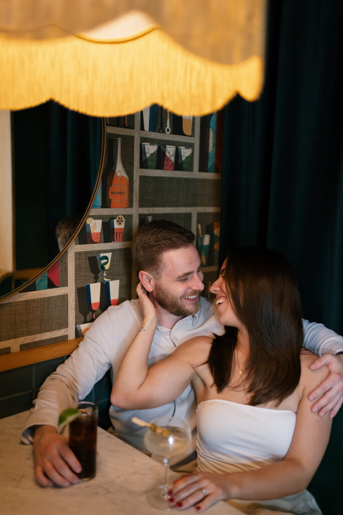 Couple laughing together in a cocktail bar booth