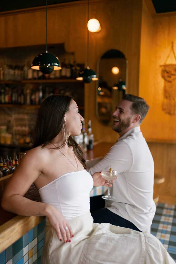 Couple sitting at a cocktail bar in Washington DC for their engagement shoot
