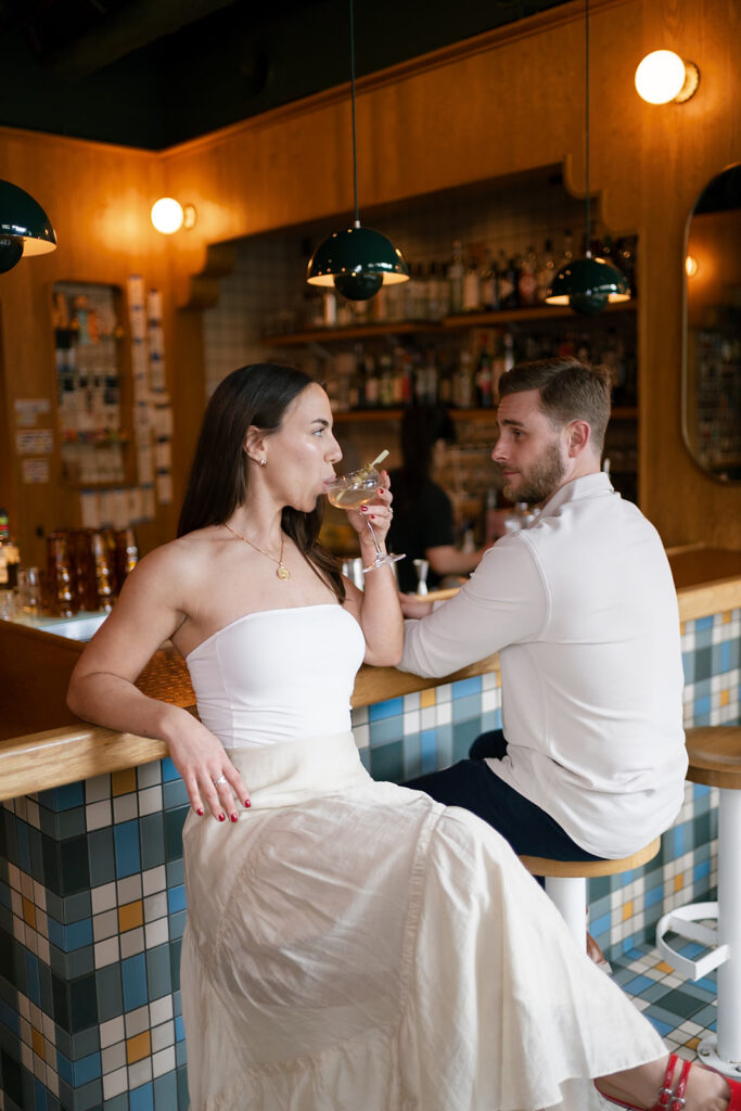 Couple sitting at a cocktail bar in Washington DC for their engagement shoot