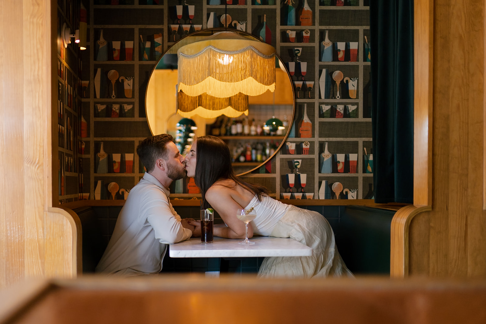 Woman leaning over a table to kiss her fiancé