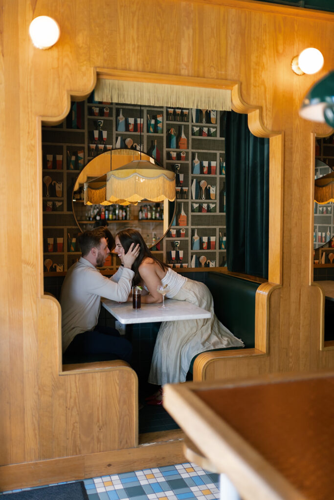 Woman leaning over a table to kiss her fiancé