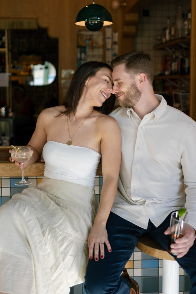Couple touching noses and smiling during their cocktail bar engagement photos