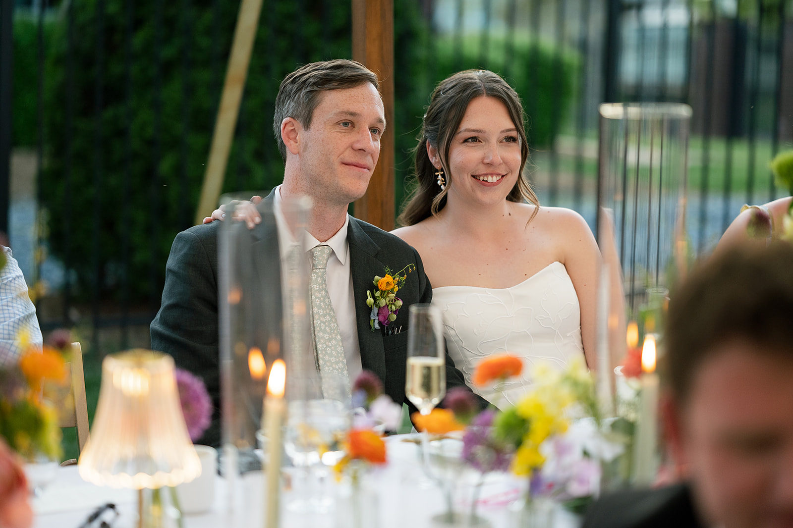 Bride and groom smiling during reception speeches