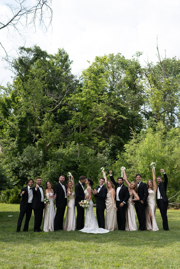 Wedding party cheering with bride and groom kissing at Daniel’s Vineyard