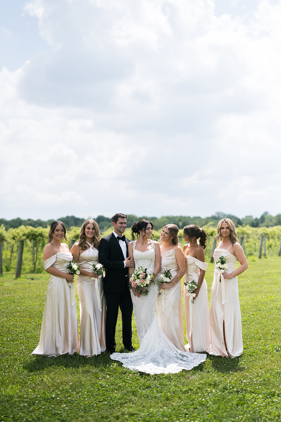 Bride with bridesmaids and man of honor smiling in vineyard at Daniel’s Vineyard