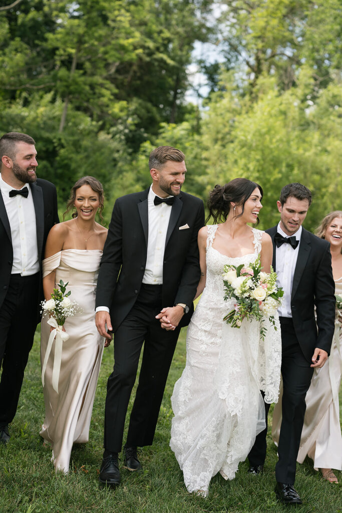 Bride and groom walking with wedding party laughing during portraits at Daniel’s Vineyard