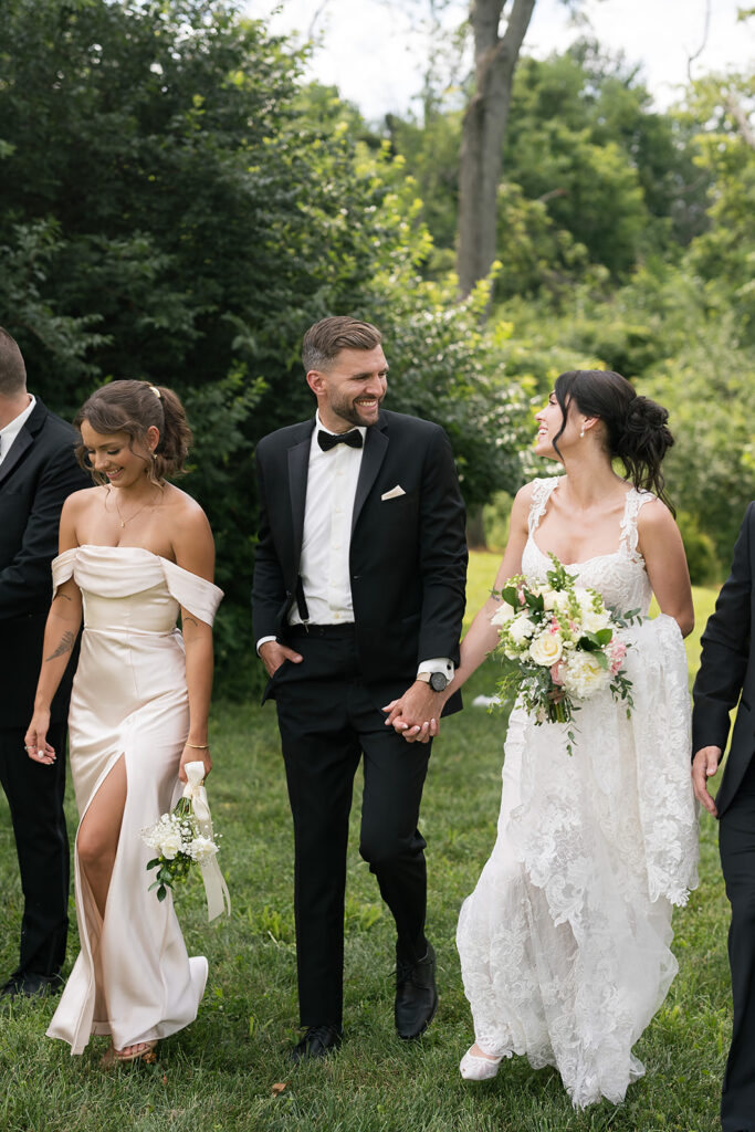 Bride and groom walking hand in hand with wedding party at Daniel’s Vineyard summer wedding