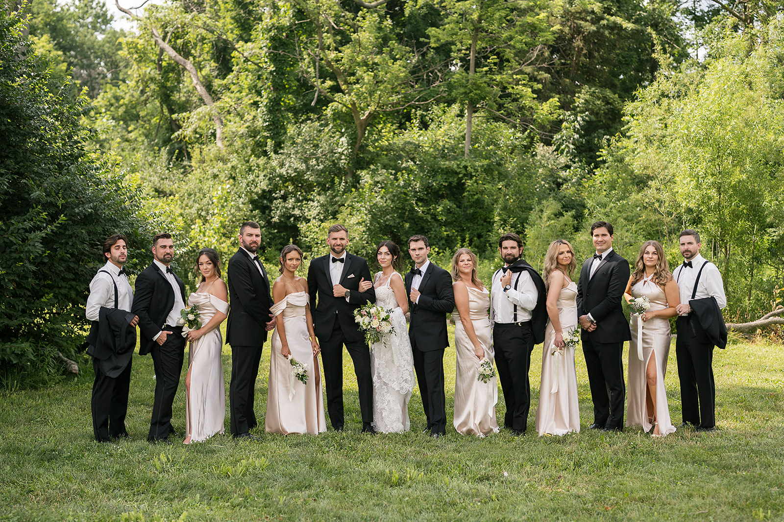Full wedding party lined up outdoors at Daniel’s Vineyard with bridesmaids in champagne gowns and groomsmen in tuxedos