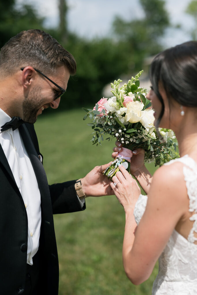 Bride showing bouquet charm to groom during outdoor portraits at Daniel’s Vineyard wedding