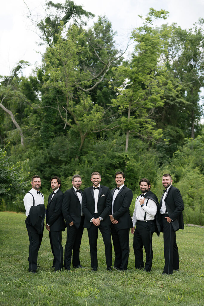 Groom posing with groomsmen in classic black tuxedos at Daniel’s Vineyard wedding